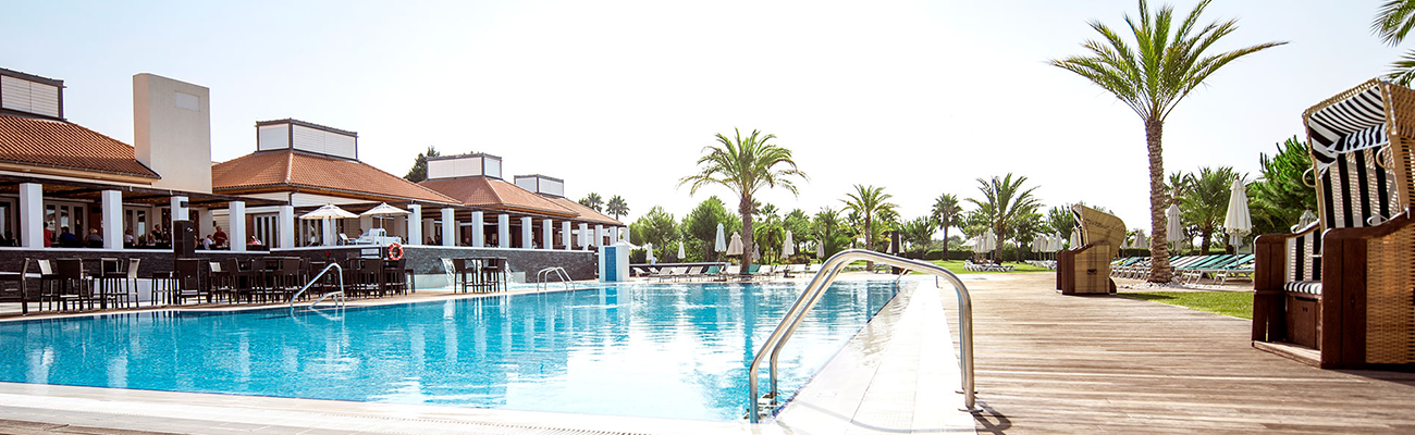 Poolanlage im ROBINSON Quinta da Ria mit Palmen, Liegen und Strandkörben an der Algarve