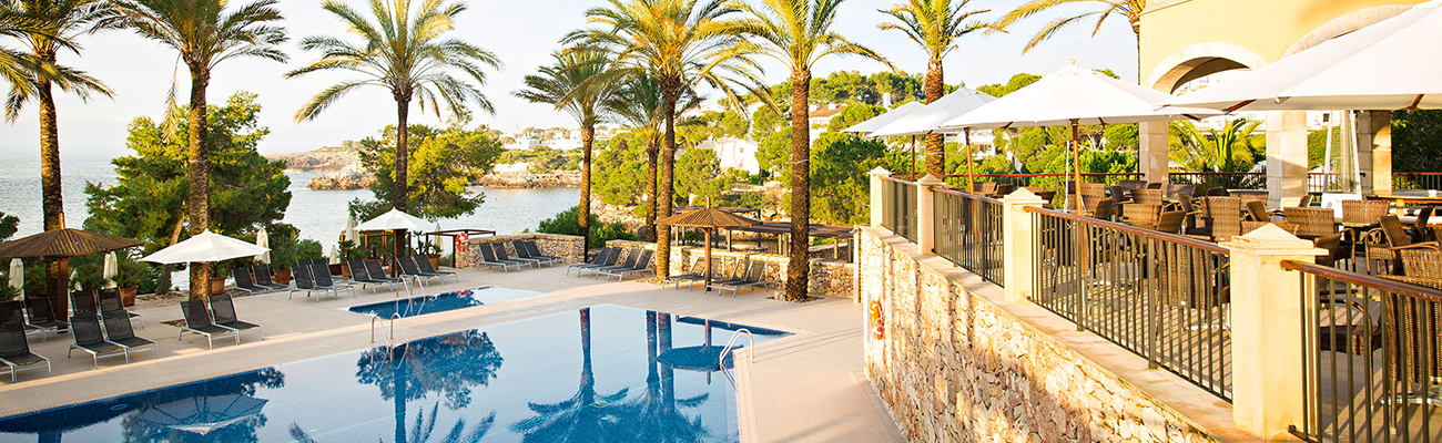Poolbereich im ROBINSON Cala Serena auf Mallorca mit Palmen, Terrasse und Blick auf das Meer