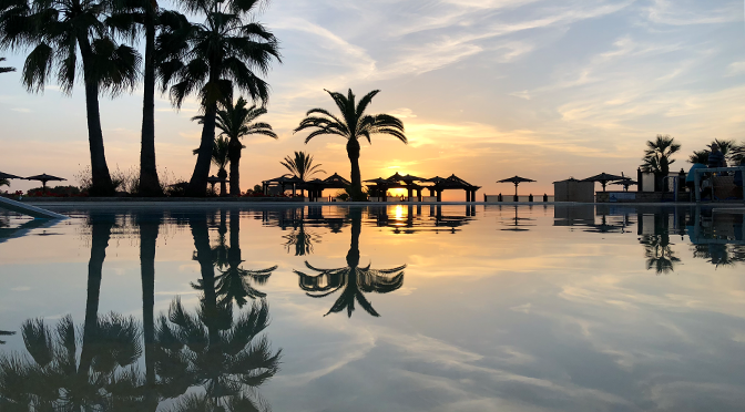 Sonnenuntergang am Pool des ROBINSON Agadir mit Palmen und Spiegelung im Wasser