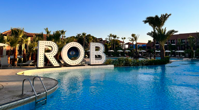 Poolbereich im ROBINSON Cyprus mit ROB-Schriftzug, Palmen und entspannter Clubatmosphäre
