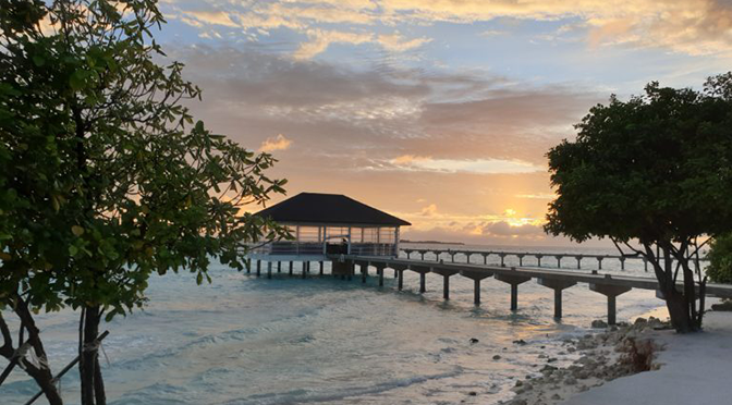 Seebrücke im ROBINSON Noonu bei Sonnenuntergang über dem Meer