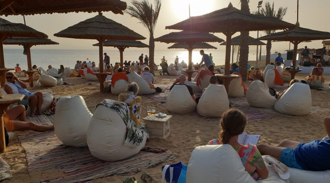 Sonnenuntergang am Strand des ROBINSON Soma Bay mit Gästen, Sitzsäcken und Meerblick
