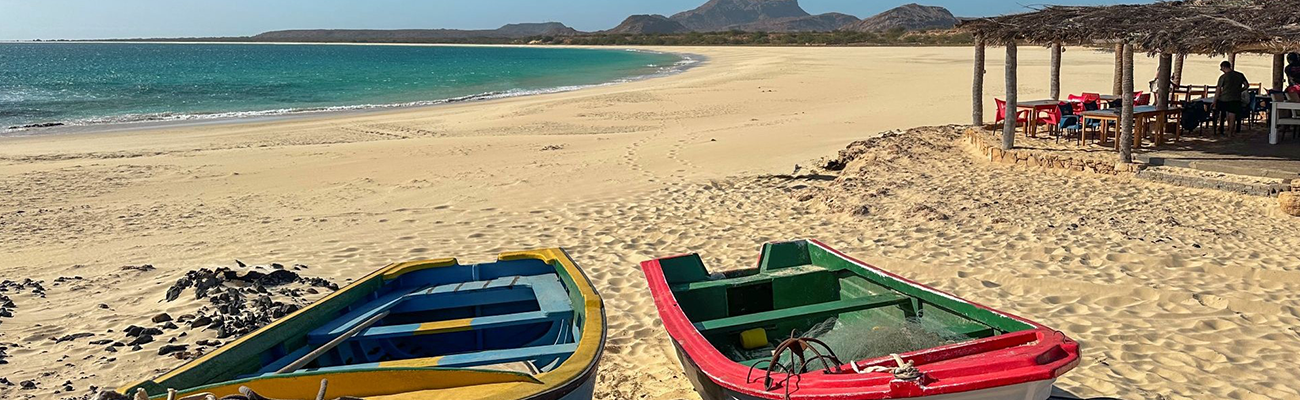 Sandstrand auf Boa Vista mit bunten Fischerbooten, türkisblauem Meer und weiter Dünenlandschaft